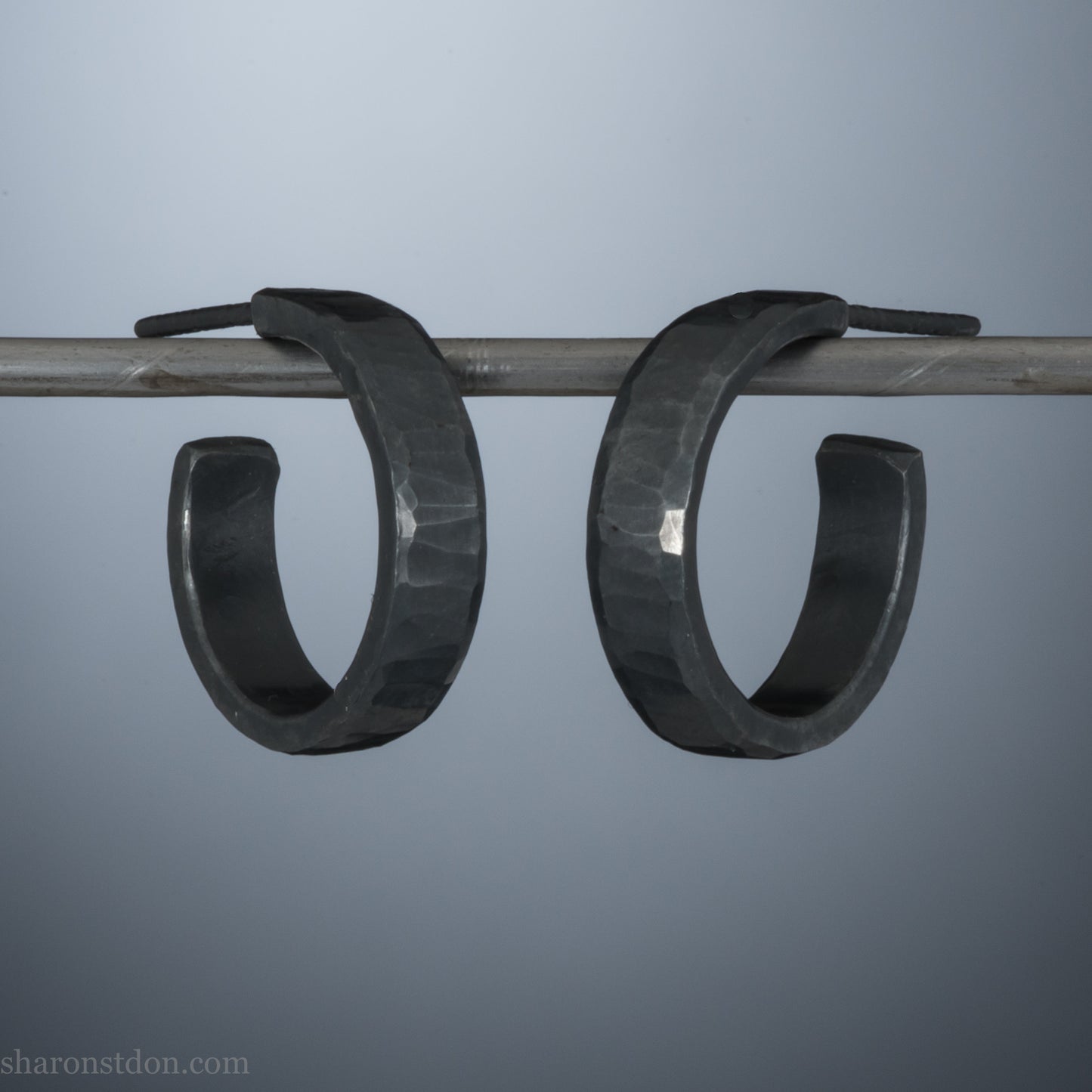 16 x 4mm x 1.5mm thick, 925 sterling silver hoop earrings. Handcrafted in the USA by Sharon Saint Don. Hammered solid silver with an oxidized black finish, silver posts and backs.