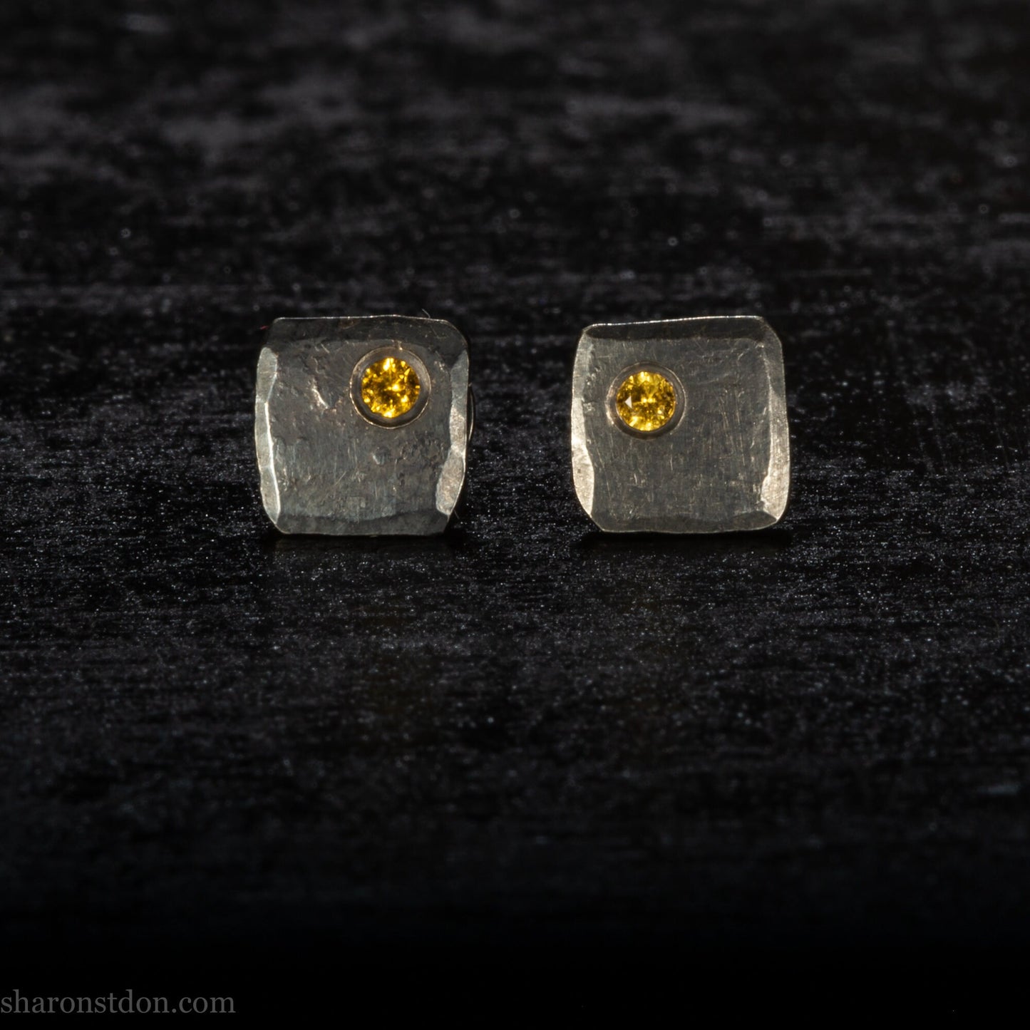Handmade 925 sterling silver stud earrings handmade by Sharon SaintDon In North America. 7mm x 7mm hammered, square, oxidized black silver with a 2mm round lab grown golden yellow topaz gemstone in the corner.