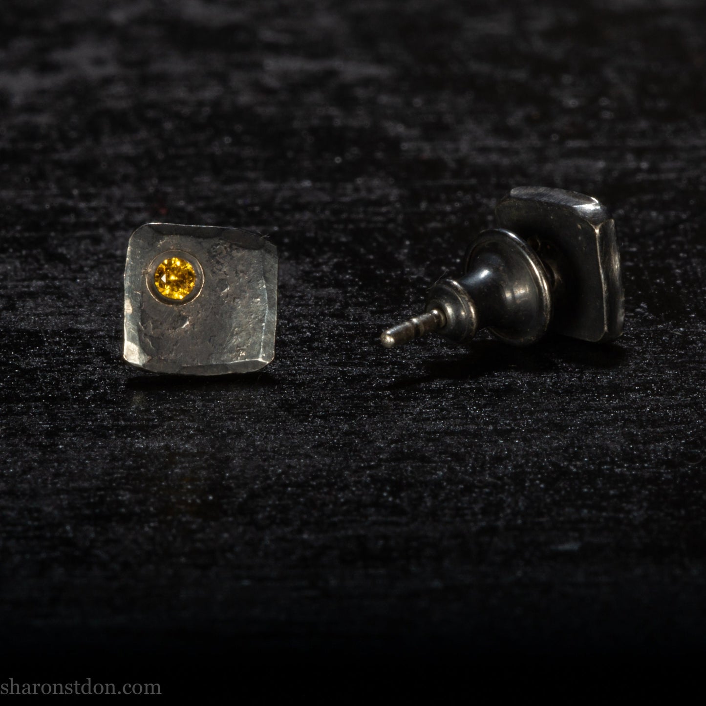 Handmade 925 sterling silver stud earrings handmade by Sharon SaintDon In North America. 7mm x 7mm hammered, square, oxidized black silver with a 2mm round lab grown golden yellow topaz gemstone in the corner.
