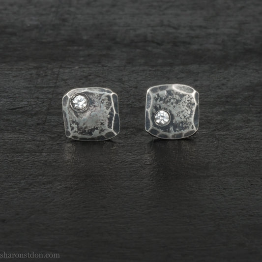 Handmade 925 sterling silver stud earrings with 2mm round moissanite lab grown gemstone set in the corner. 7mm square, 1.5mm thick, solid hammered silver with antiqued, dark finish. Posts and backs are sterling silver.