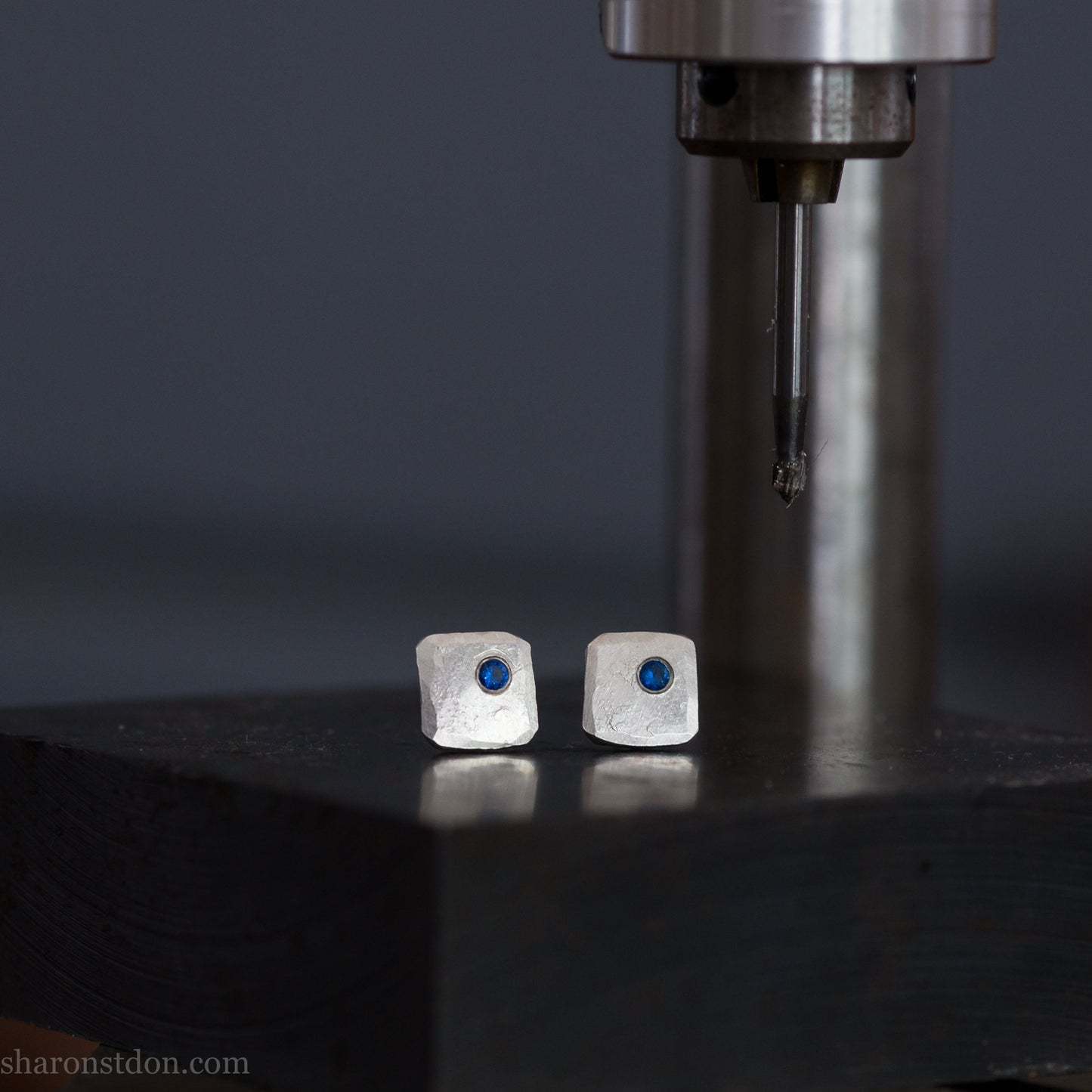 Handmade 925 sterling silver stud earrings for men with 2mm, lab grown blue spinel gemstone set in the corner. 7mm square, 1.5mm thick with silver posts and backs and hammered, matte, brushed finish. Handmade by Sharon SaintDon in North America.