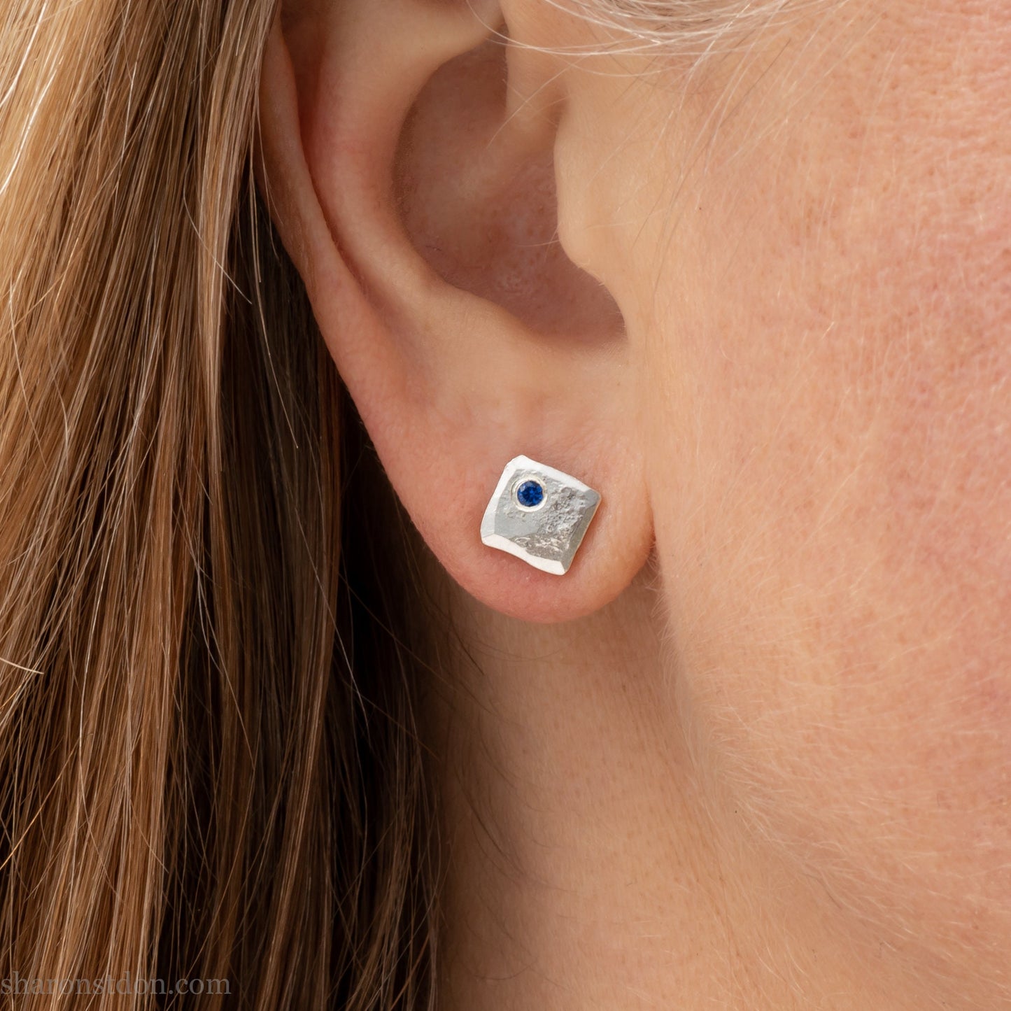 Handmade 925 sterling silver stud earrings for men with 2mm, lab grown blue spinel gemstone set in the corner. 7mm square, 1.5mm thick with silver posts and backs and hammered, matte, brushed finish. Handmade by Sharon SaintDon in North America.