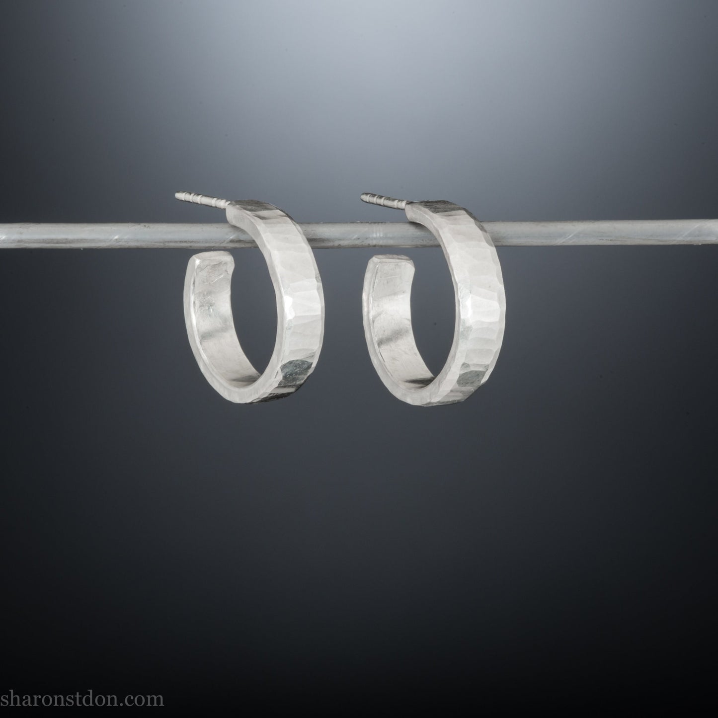 Small sterling silver hoop earrings, Handmade in North America by Sharon SaintDon. 18 x 4 x 1.5mm thick. Solid hammered silver with a matte, brushed finish, silver posts and backs.