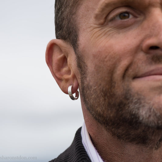 Small sterling silver hoop earrings, Handmade in North America by Sharon SaintDon. 18 x 4 x 1.5mm thick. Solid hammered silver with a matte, brushed finish, silver posts and backs.