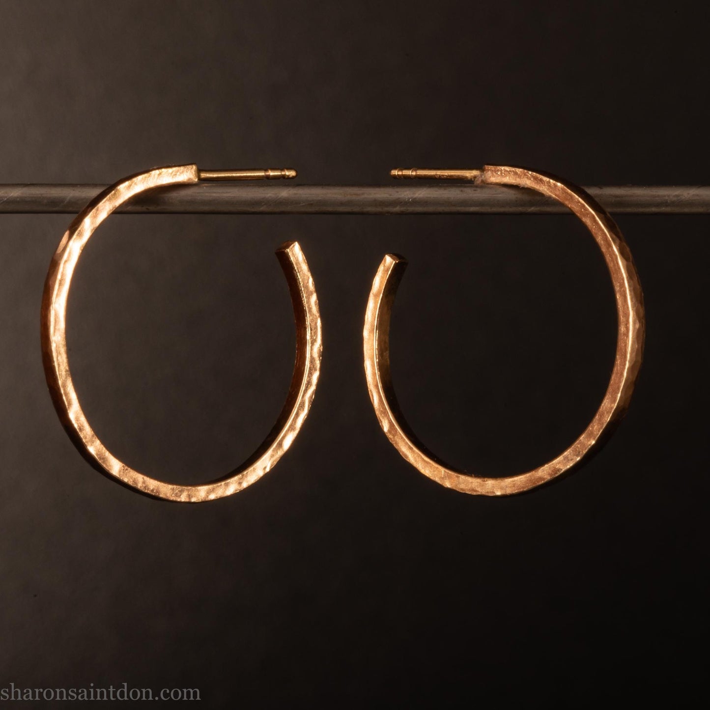 25mm diameter by 1.5mm thick solid 14k yellow gold hoop earrings. Solid 14k gold posts and backs. Handmade by Sharon SaintDon in North America. Hammered from solid gold with a matte finish.