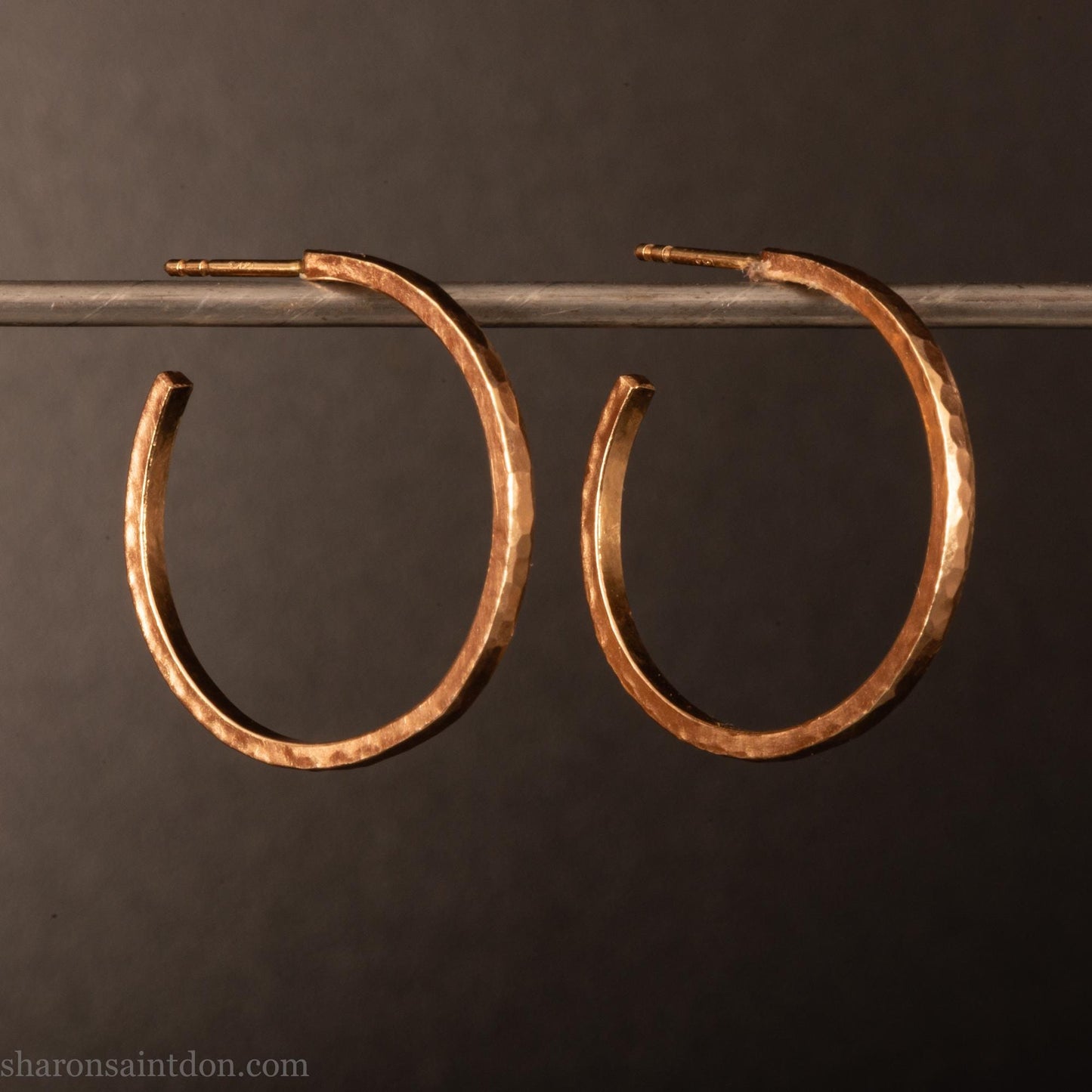 25mm diameter by 1.5mm thick solid 14k yellow gold hoop earrings. Solid 14k gold posts and backs. Handmade by Sharon SaintDon in North America. Hammered from solid gold with a matte finish.