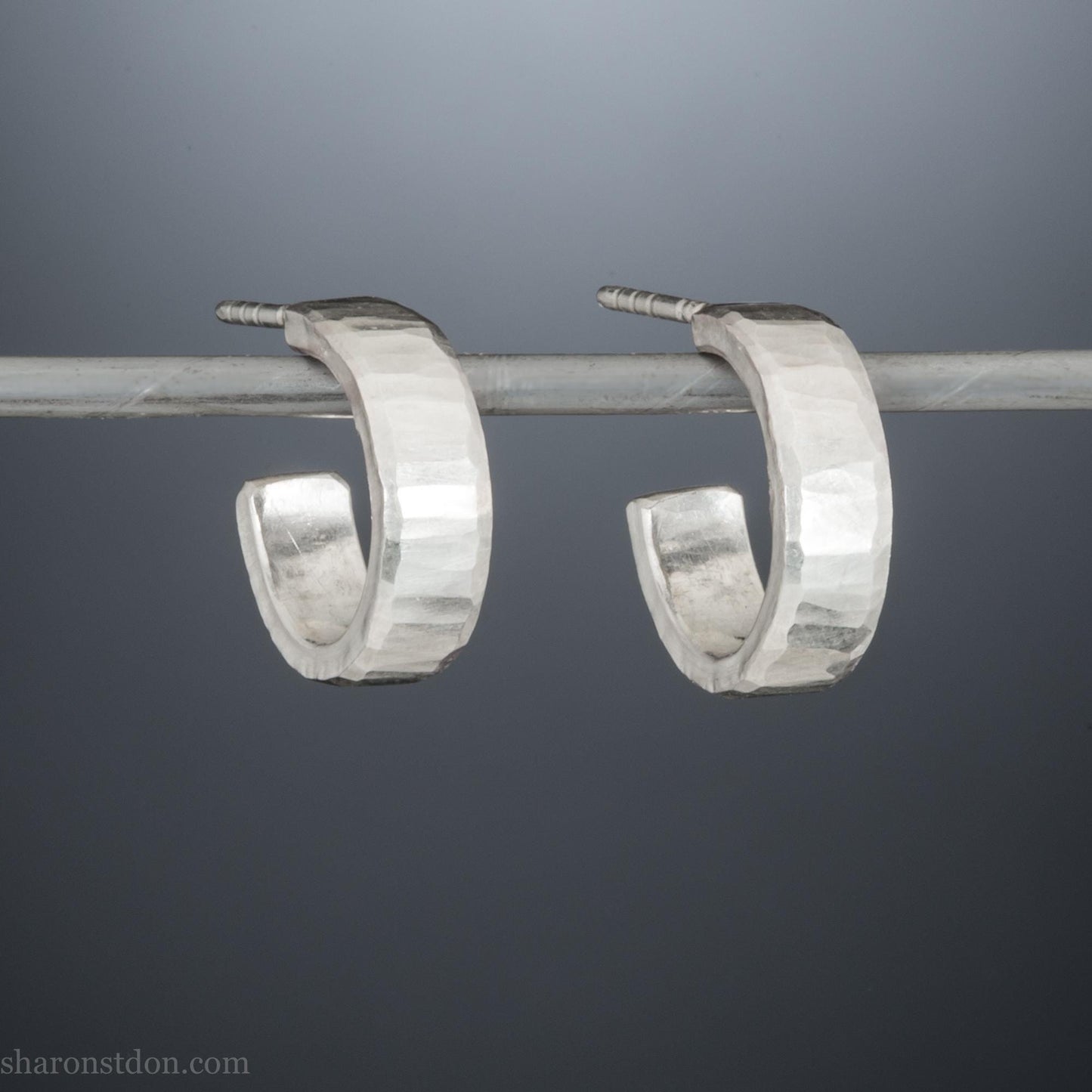 Solid sterling silver hoop earrings handmade in North America by Sharon SaintDon. Solid hammered silver with a matte brushed finish. 14mm diameter, 4mm wide, 1.5mm thick, solid silver posts and backs.