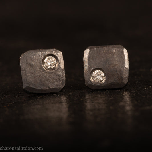 Handcrafted 7mm square sterling silver stud earrings, oxidized black with a 2mm round moissanite gemstone set in the corner.