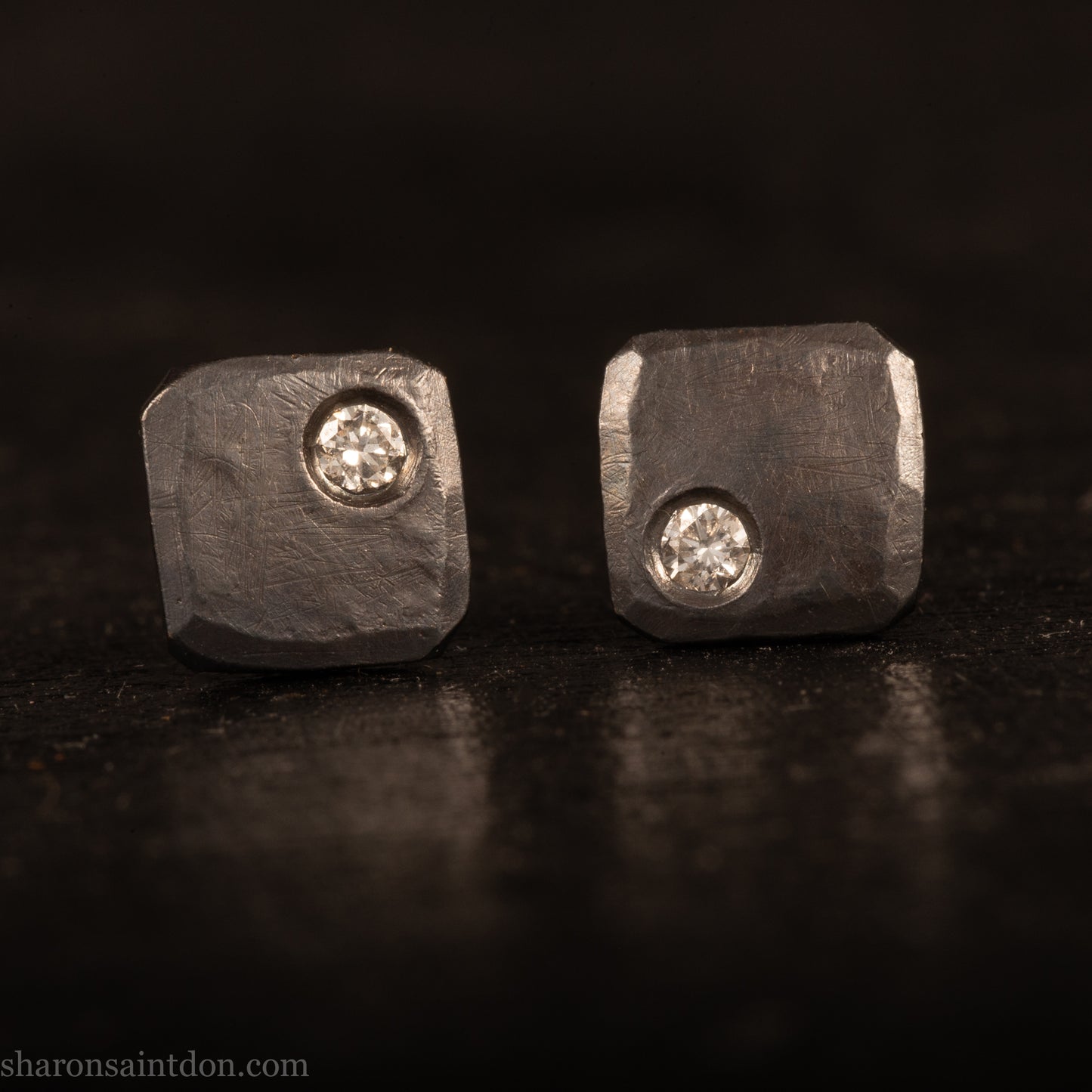 Handcrafted 925 sterling silver stud earrings with moissanite, lab grown, alternative diamond gemstones. 7mm square, 1.5mm thick, solid hammered silver with oxidized black finish. 2mm round moissanite is set in the corner, posts and backs are sterling silver.