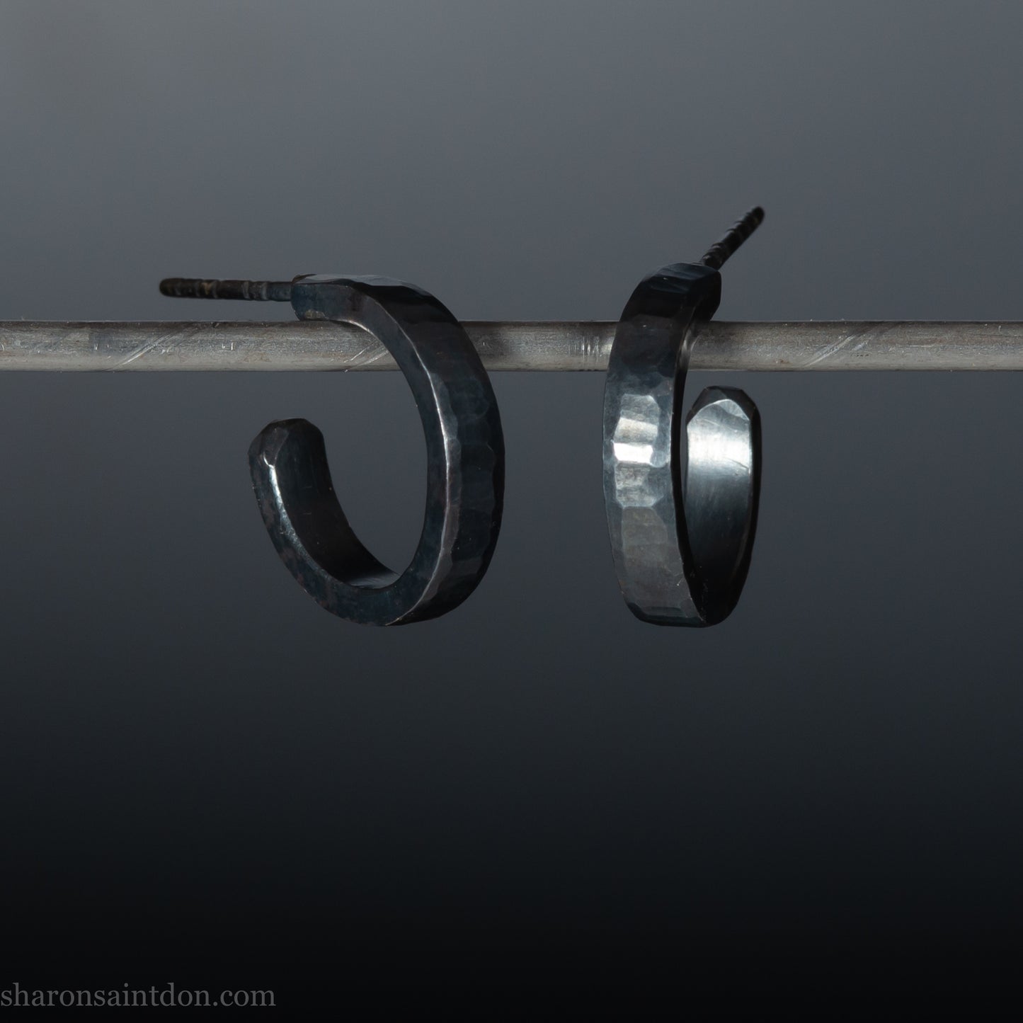 Solid 925 sterling silver hoop earrings with an oxidized, matte, black finish. 18mm exterior diameter, 15mm interior, 3mm wide, and 1.5mm thick. Solid sterling silver posts and backs. Handcrafted in the USA, each pair hand hammered by Sharon Saint Don.