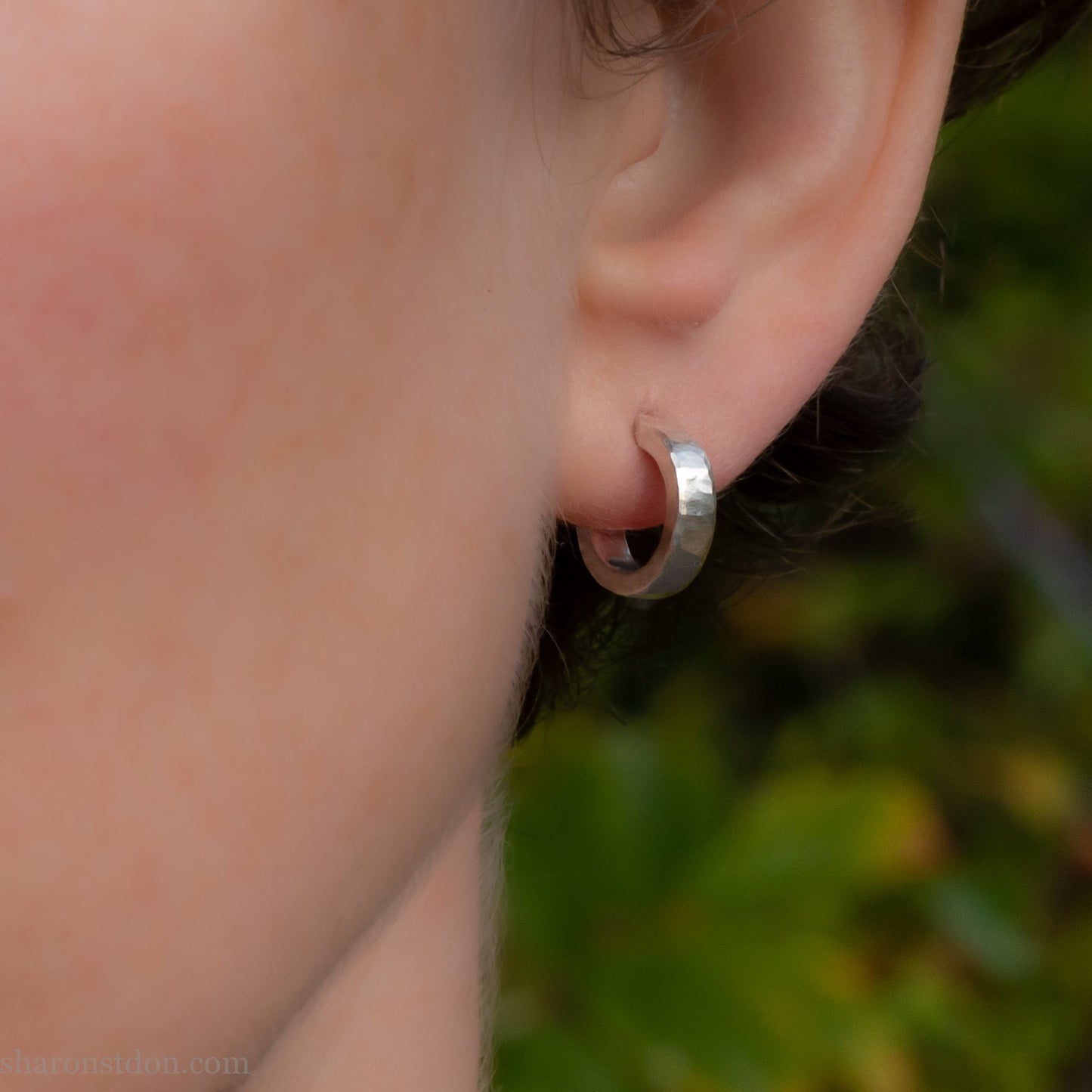 Hammered solid 925 silver hoop earrings with a matte shiny finish. 12mm exterior diameter, 9mm interior, 3mm wide and 1.5mm thick. Solid sterling silver posts and backs. Handcrafted by Sharon Saint Don in the USA. Pictured on fair skinned person.