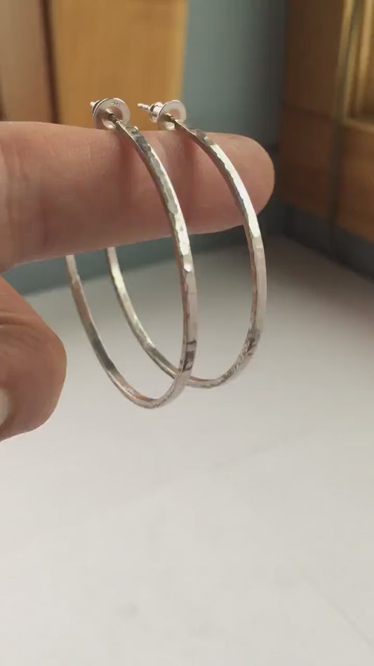 Solid 925 sterling silver hoop earrings. 50mm diameter, 2mm wide, 1.5mm thick with a matte, shiny finish. Lightweight hammered large hoop earrings handmade by Sharon SaintDon in North America.