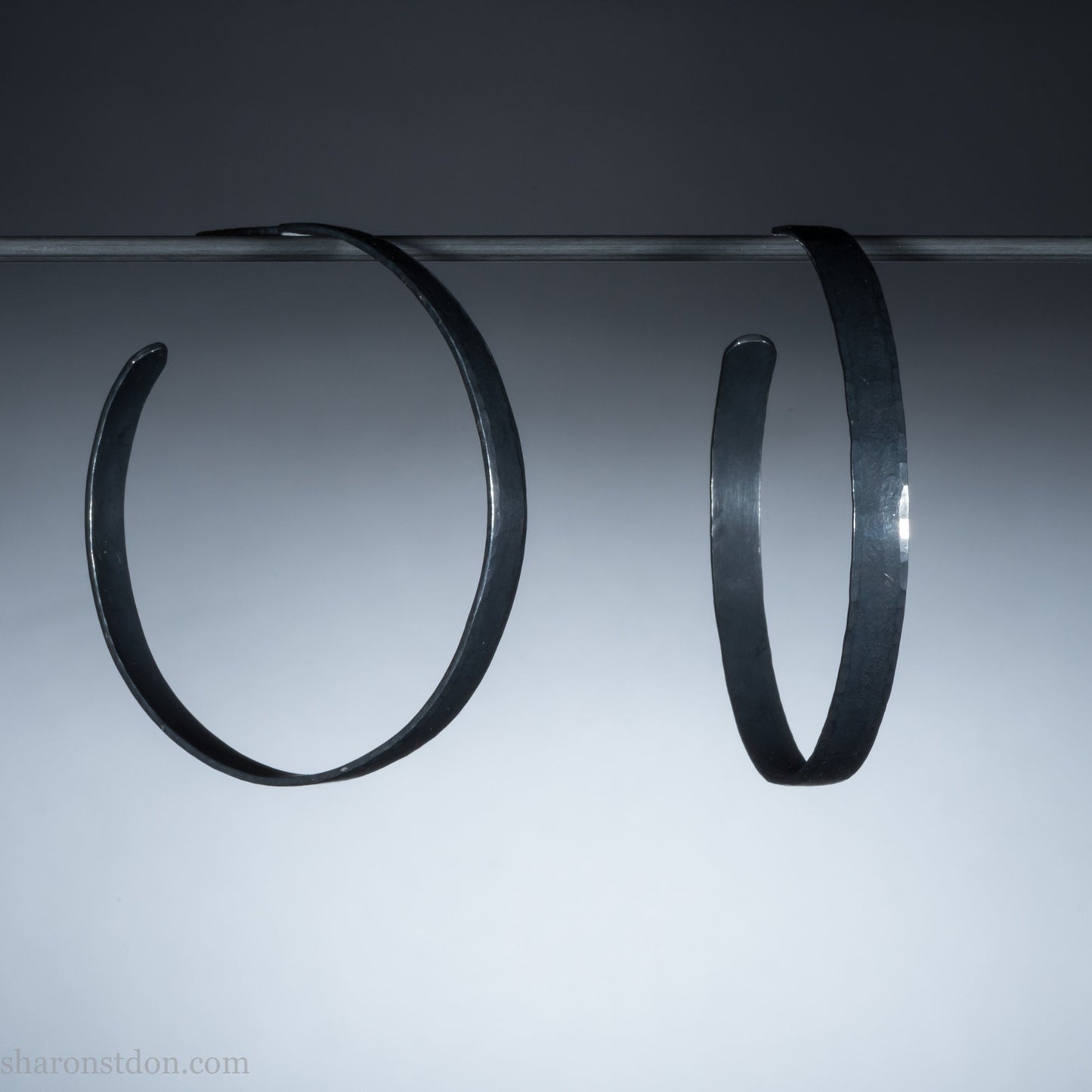 Solid 925 sterling silver hoop earrings. 50mm diameter, 5mm wide, .75mm thick. Oxidized black, charcoal grey, matte finish with silver posts and backs. lightweight, high quality, handmade by Sharon SaintDon in the Pacific Northwest of the USA.