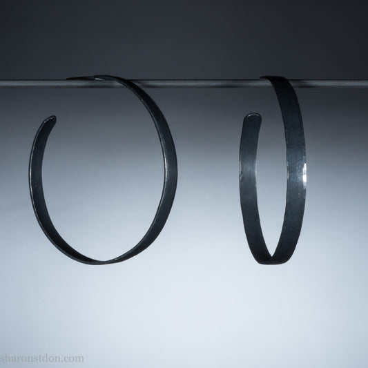 Solid 925 sterling silver hoop earrings. 50mm diameter, 5mm wide, .75mm thick. Oxidized black, charcoal grey, matte finish with silver posts and backs. lightweight, high quality, handmade by Sharon SaintDon in the Pacific Northwest of the USA.
