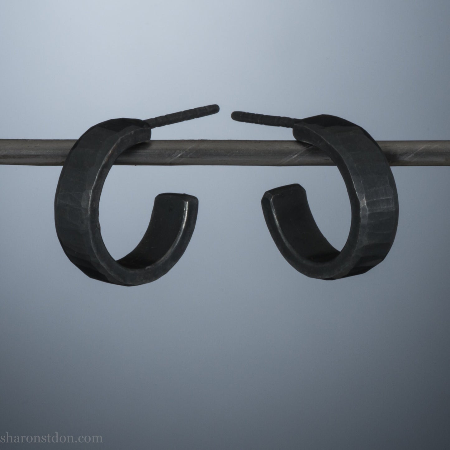 Close up photo of handcrafted oxidized black 14mm x 4mm hammered solid sterling silver hoop earrings.