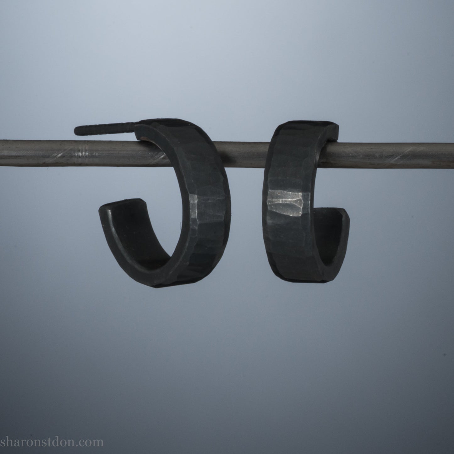 Close up photo of handcrafted oxidized black 14mm x 4mm hammered solid sterling silver hoop earrings.