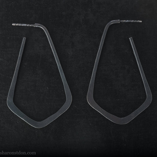 Hand hammered 925 sterling silver hoop earrings that are long, angular, teardrop shaped and oxidized black. SIZE: 5cm high x 32mm wide.