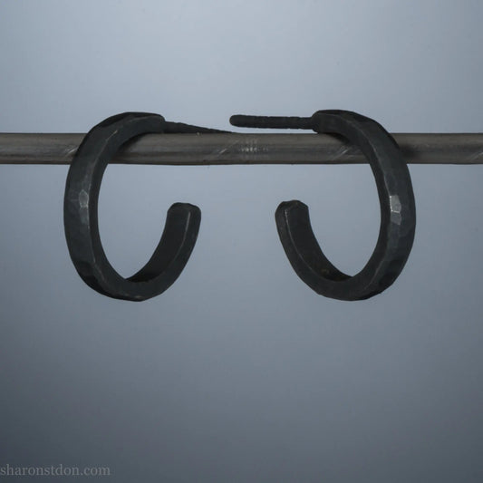 14mm x 2mm small sterling silver hoop earrings, oxidized black. Handmade in North America by Sharon SaintDon. Hammered texture, solid silver with silver posts and backs for men or women, unisex.