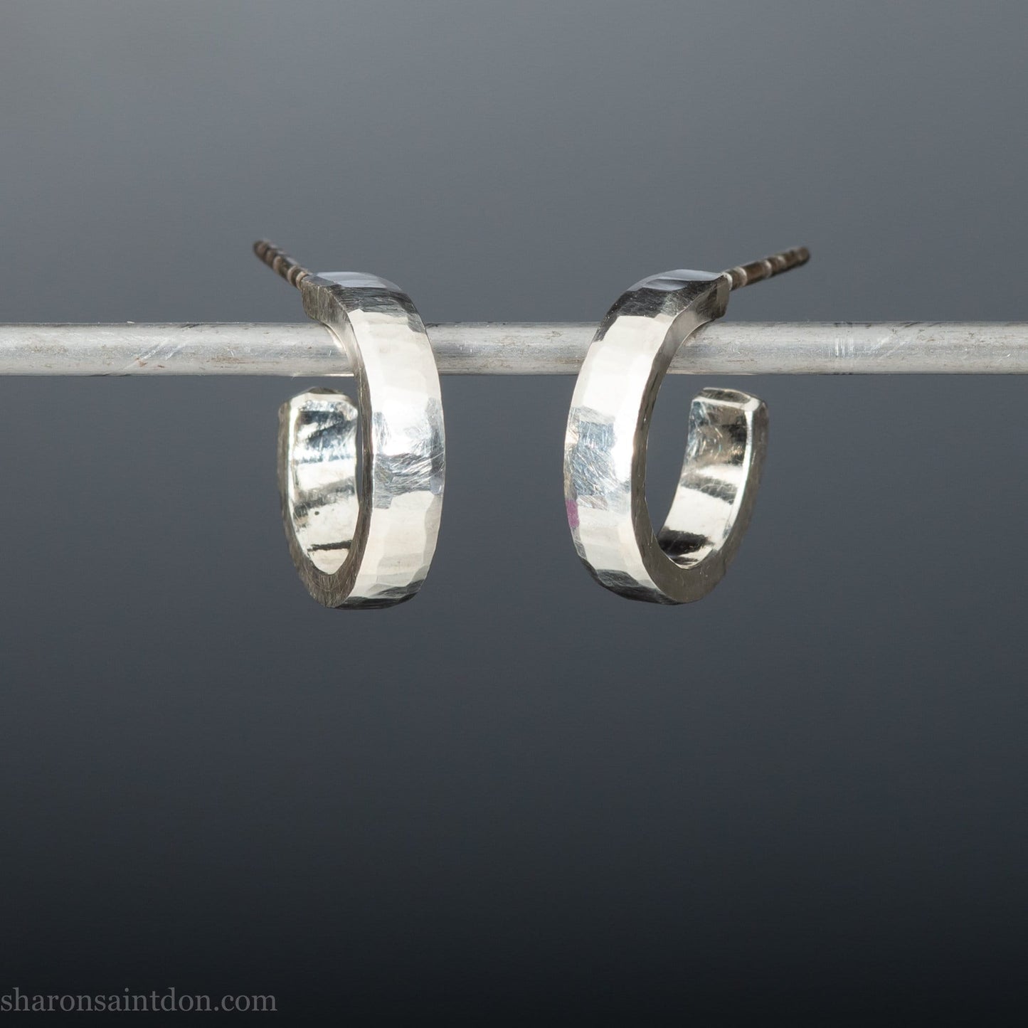 14mm x 3mm small sterling silver hoop earrings. Handmade in North America by Sharon SaintDon. Hammered solid silver with silver posts and backs.