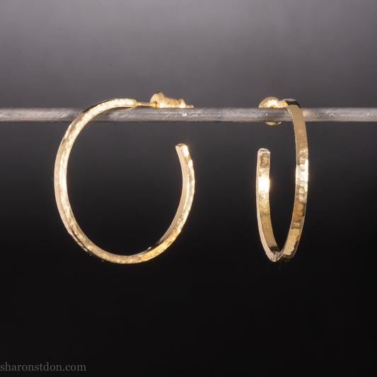 Solid hammered yellow gold hoop earrings with brushed, matte finish, gold posts and locking backs.