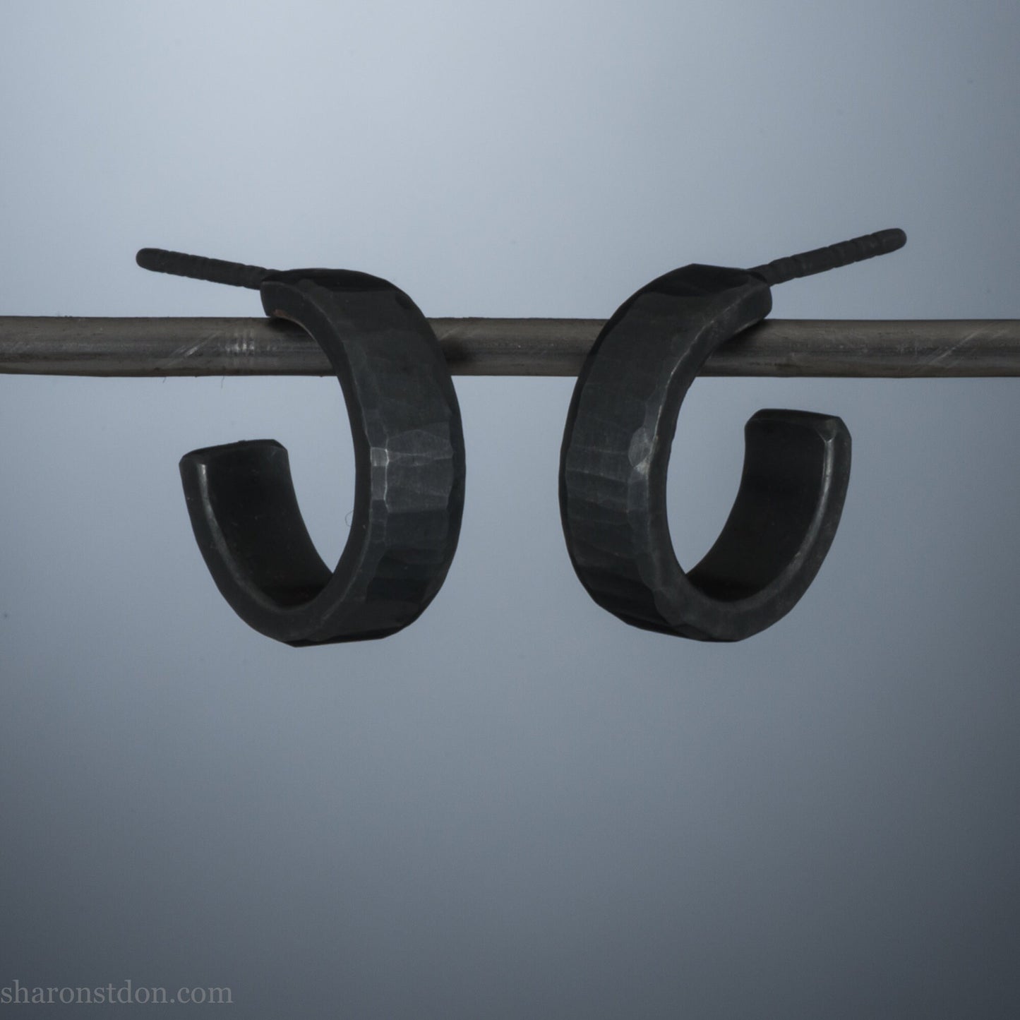 Close up photo of handcrafted oxidized black 14mm x 4mm hammered solid sterling silver hoop earrings.