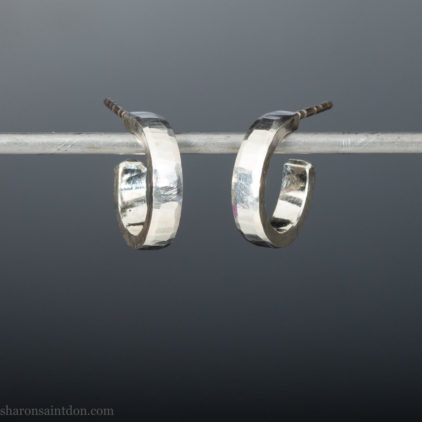 Close up photo of handcrafted 14mm x 3mm hammered solid sterling silver hoop earrings.