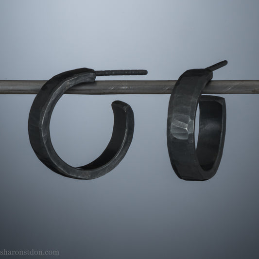 18mm x 4mm small sterling silver hoop earrings for for men or women, unisex. Handmade in North America by Sharon SaintDon. Hammered texture,solid silver with silver posts and backs oxidized black minimalist earrings