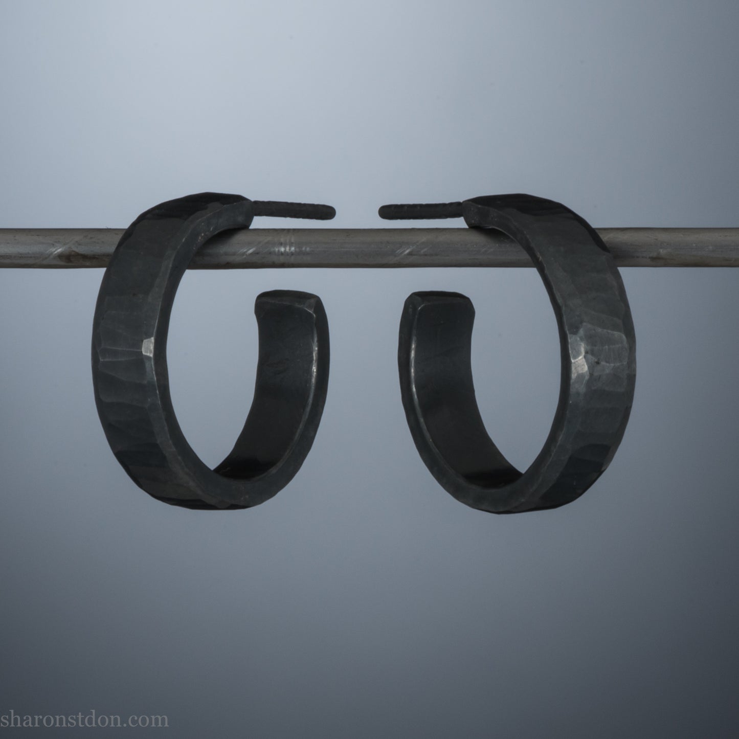18mm x 4mm small sterling silver hoop earrings for for men or women, unisex. Handmade in North America by Sharon SaintDon. Hammered texture,solid silver with silver posts and backs oxidized black minimalist earrings