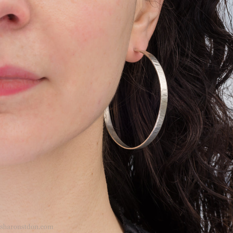 Large sterling silver hammered hoop earring, close-up on model’s ear, 55mm diameter, 4 mm wide