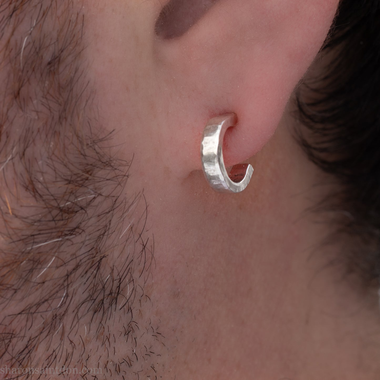 A close-up view of a person's ear with a silver hoop earring.