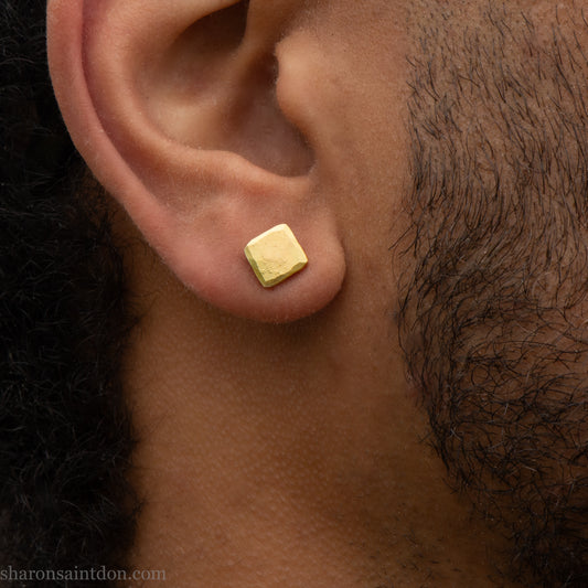 Solid 18k gold stud earrings 7mm square. Hammered with matte brushed finish, solid 18k gold posts and locking backs. Handcrafted in the USA by Sharon Saint Don. Worn by a man with dark skin, black hair and beard.