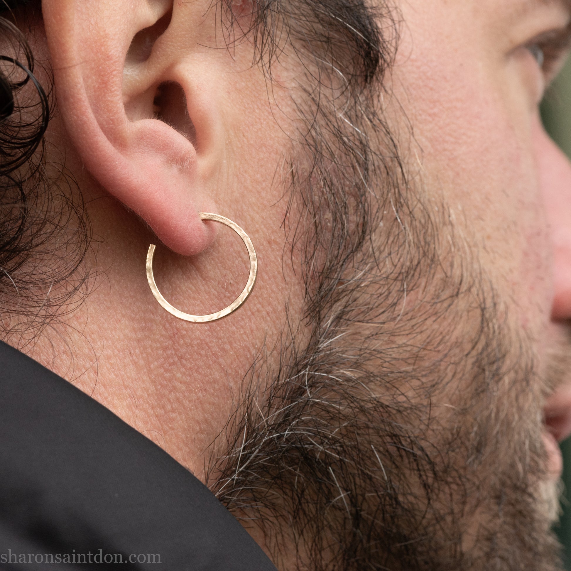 Hand hammered solid gold hoop earrings with a matte finish. 20mm diameter x 2mm wide x 1.5mm thick, worn on an ear.