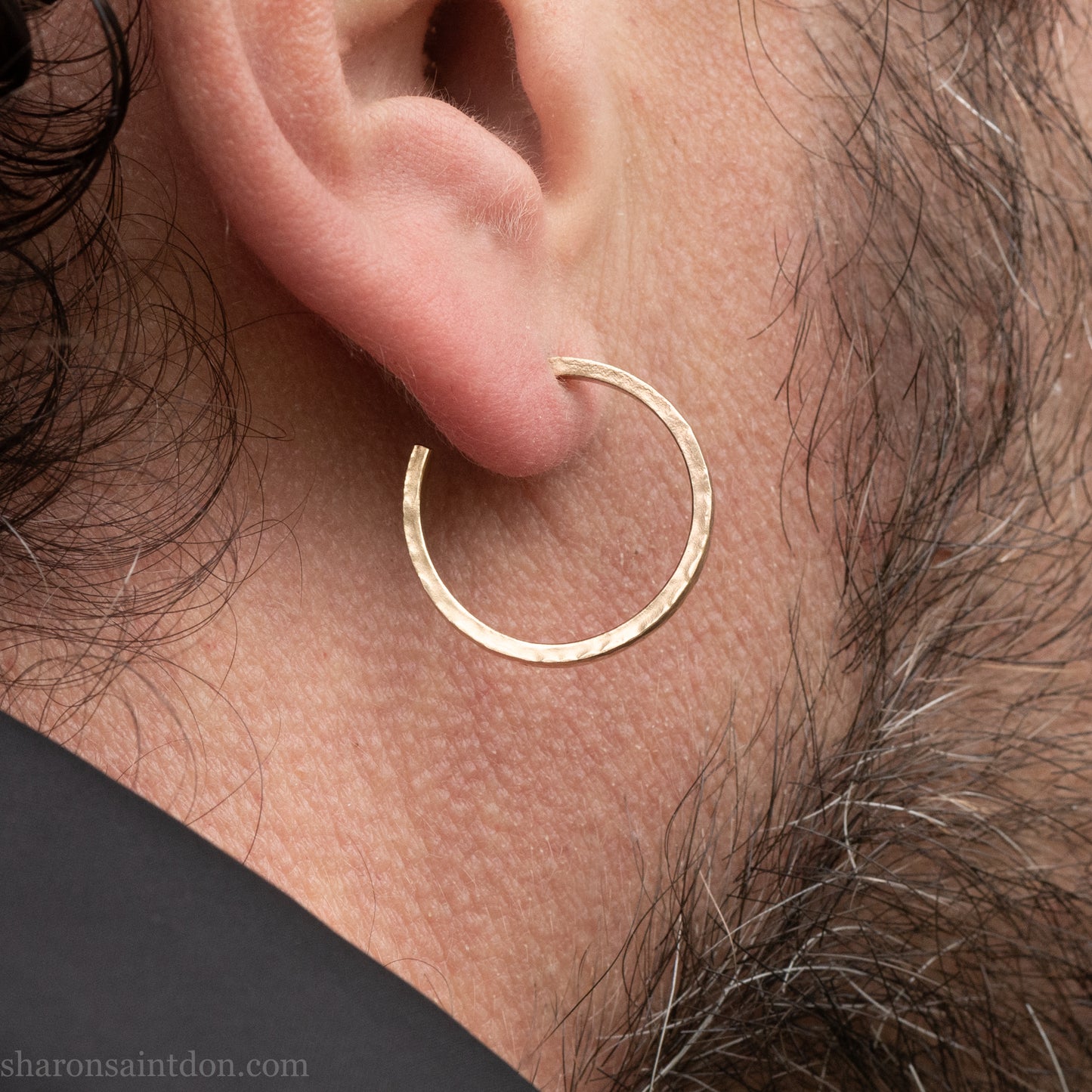 Hand hammered solid gold hoop earrings with a matte finish. 20mm diameter x 2mm wide x 1.5mm thick, worn on an ear.