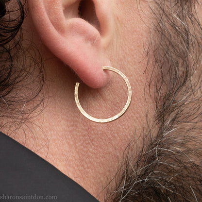 Hand hammered solid gold hoop earrings with a matte finish. 20mm diameter x 2mm wide x 1.5mm thick, worn on an ear.