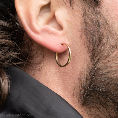 Hand hammered solid gold hoop earrings with a matte finish. 20mm diameter x 2mm wide x 1.5mm thick, worn on an ear.
