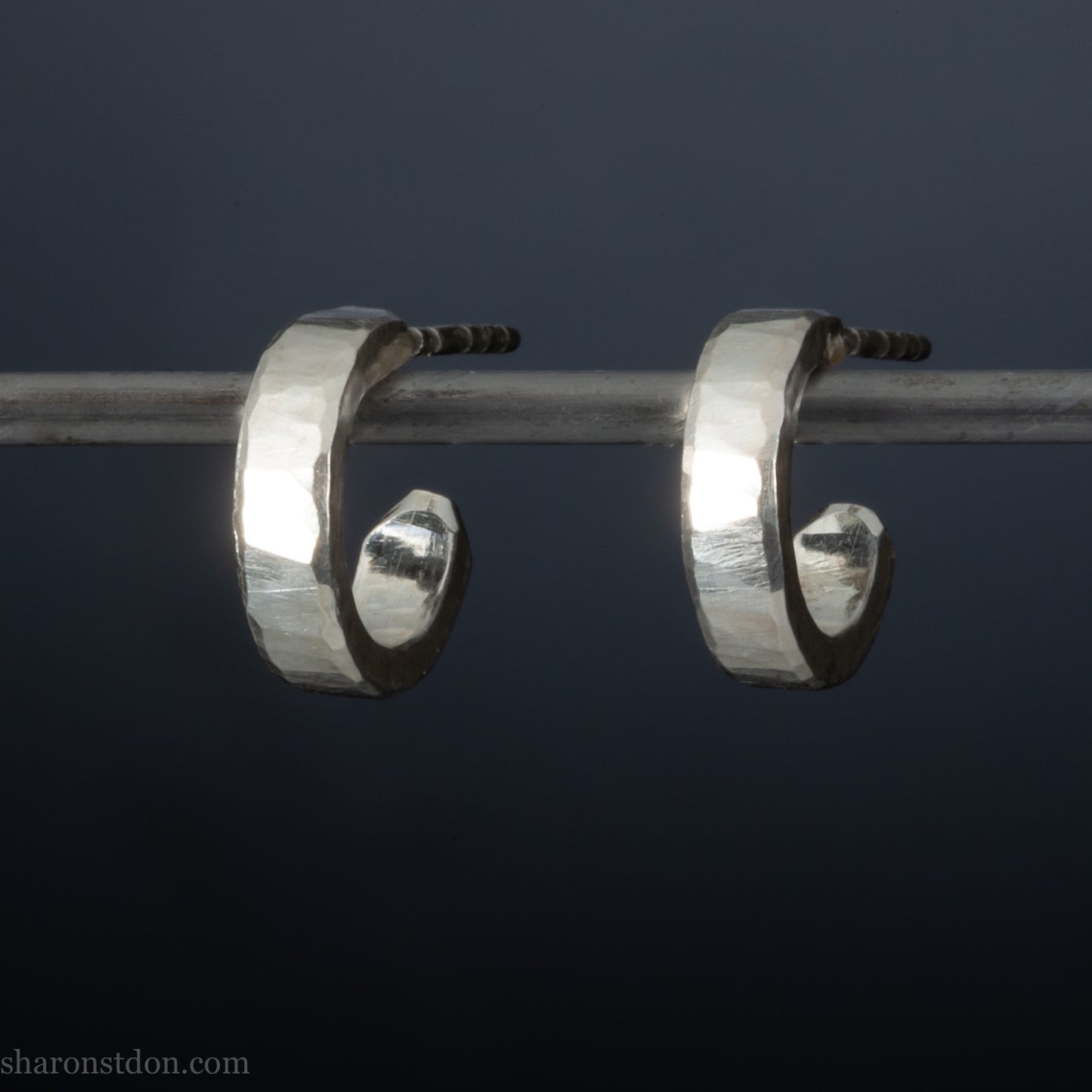 A close-up view of handcrafted solid silver hoop earrings, 12mm diameter x 3mm wide x 1.5mm thick with a hammered matte finish.