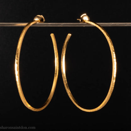 Solid 22k yellow gold hoop earrings for women. 55mm diameter, 1.5mm wide, 18k posts and locking backs. Handmade in the USA by Sharon Saint Don. Solid hammered yellow gold with sparkly, matte, brushed finish.