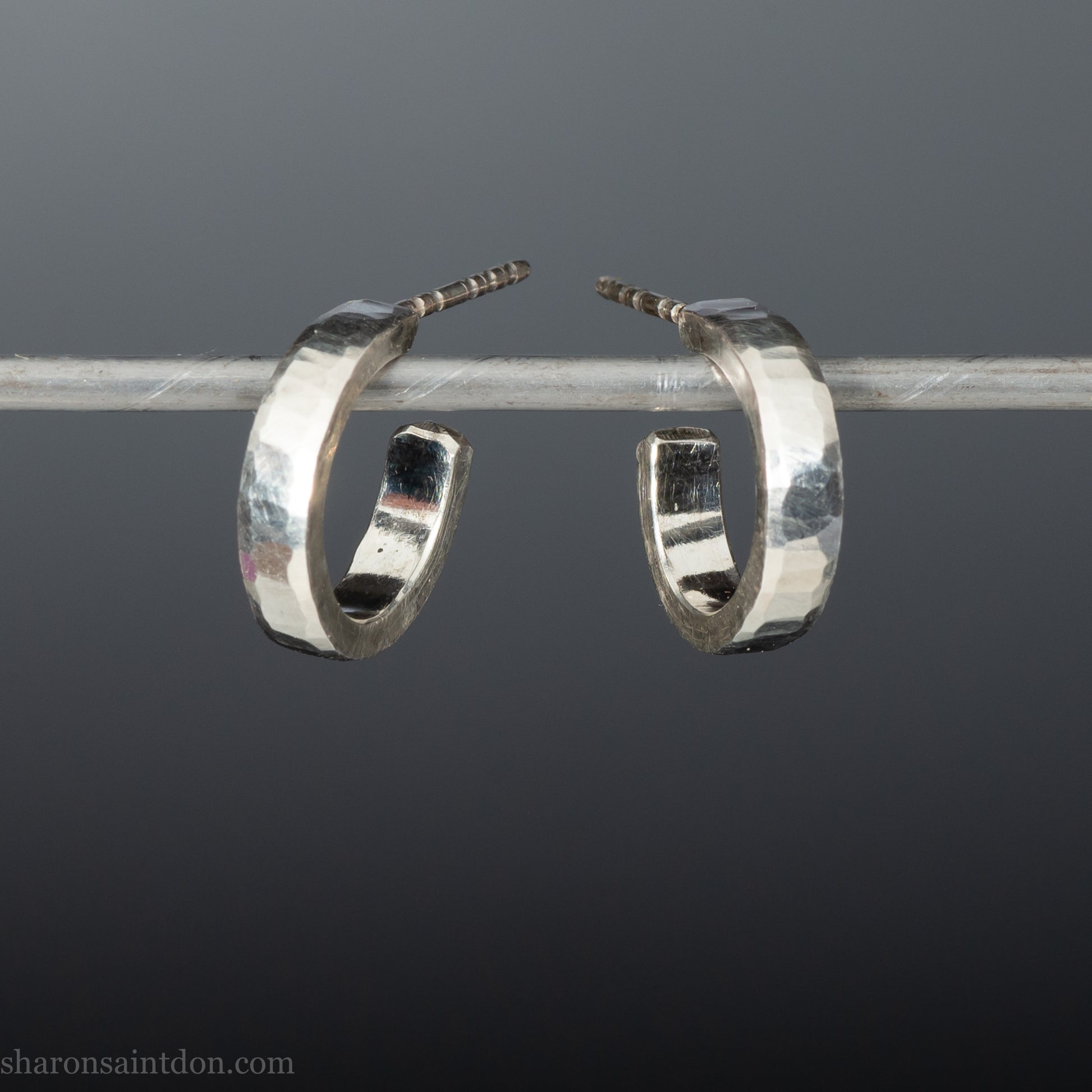 A close-up view of handcrafted solid silver hoop earrings, 14mm diameter x 3mm wide x 1.5mm thick with a hammered matte finish.