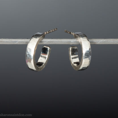 A close-up view of handcrafted solid silver hoop earrings, 14mm diameter x 3mm wide x 1.5mm thick with a hammered matte finish.