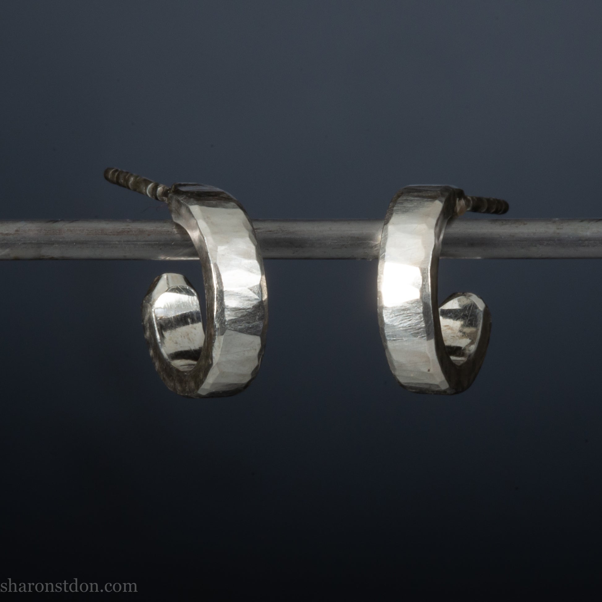 A close-up view of handcrafted solid silver hoop earrings, 12mm diameter x 3mm wide x 1.5mm thick with a hammered matte finish.