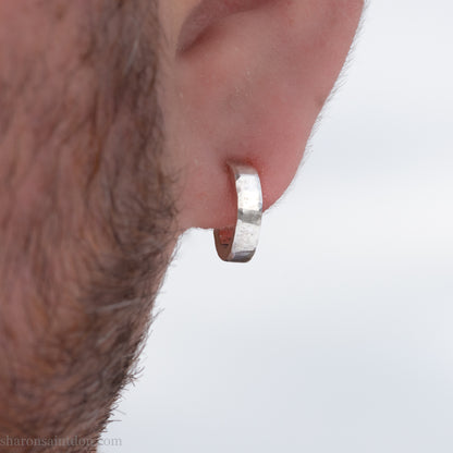 A close-up view of a person's ear with a silver hoop earring.