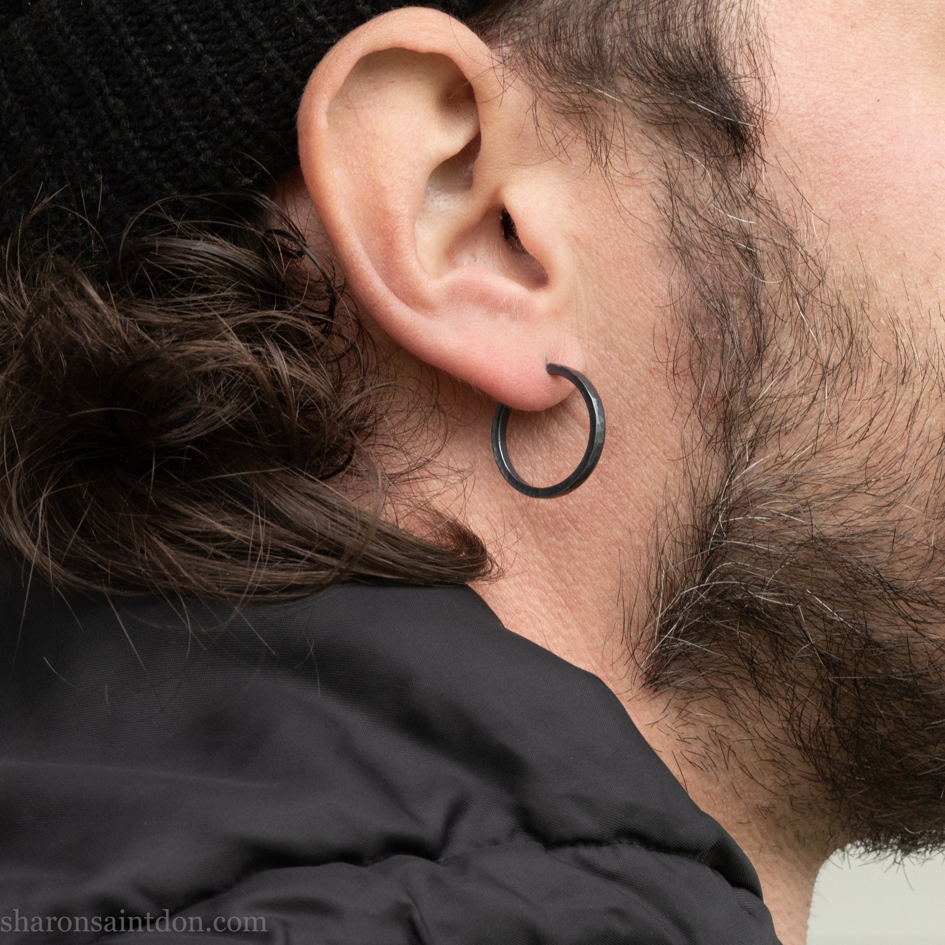 Hand hammered 925 sterling silver hoop earrings with an oxidized black finish. 20mm diameter x 2mm wide x 1.5mm thick, worn on an ear.