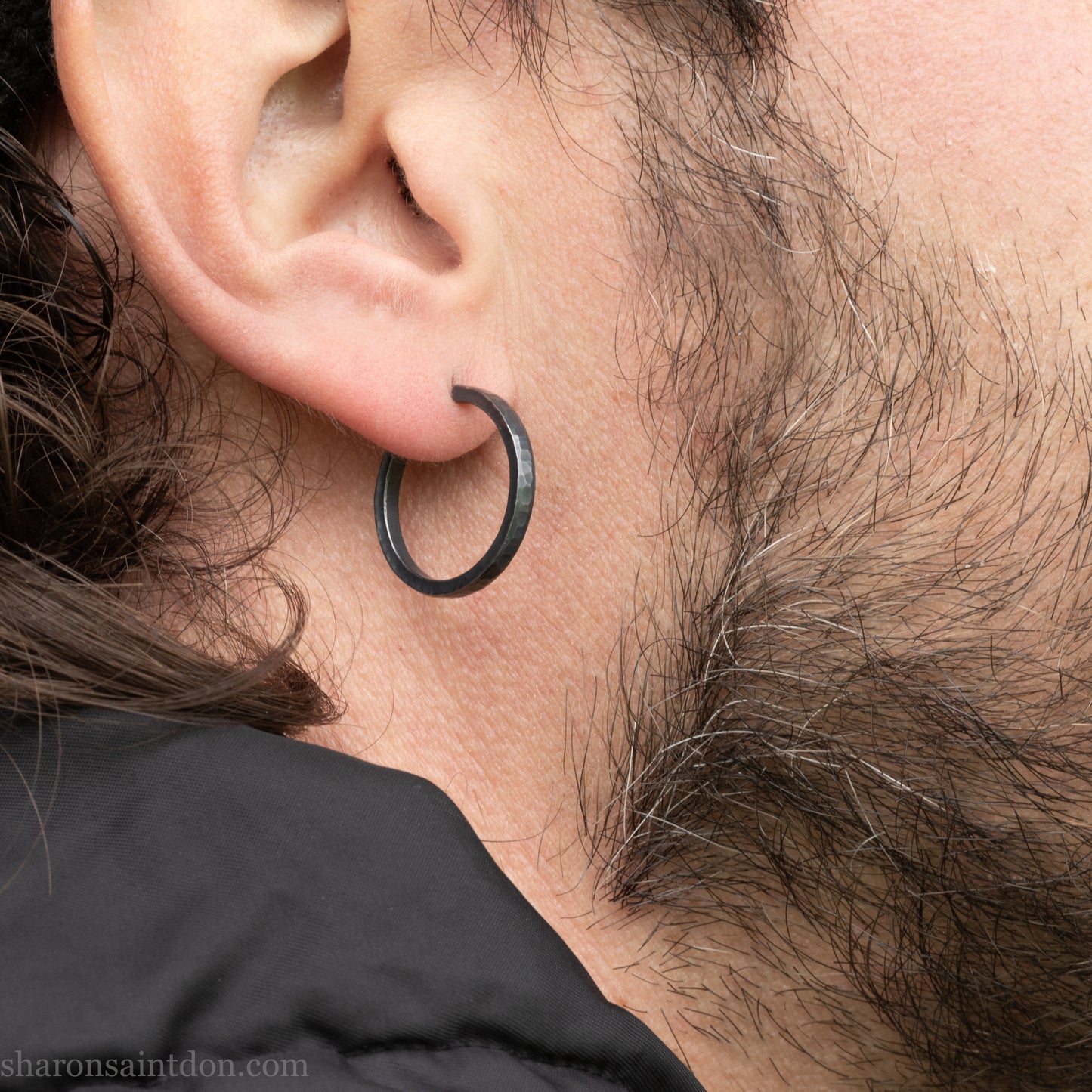 Hand hammered 925 sterling silver hoop earrings with an oxidized black finish. 20mm diameter x 2mm wide x 1.5mm thick, worn on an ear.