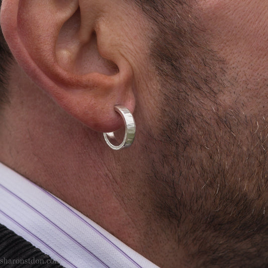 Hand hammered solid 925 sterling silver hoop earrings with a matte, brushed finish. 18mm diameter x 4mm wide x 1.5mm thick, worn by a man with a beard.
