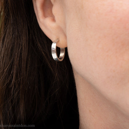 Hand hammered solid 925 sterling silver hoop earrings with a matte, brushed finish. 18mm diameter x 4mm wide x 1.5mm thick, worn on ear.