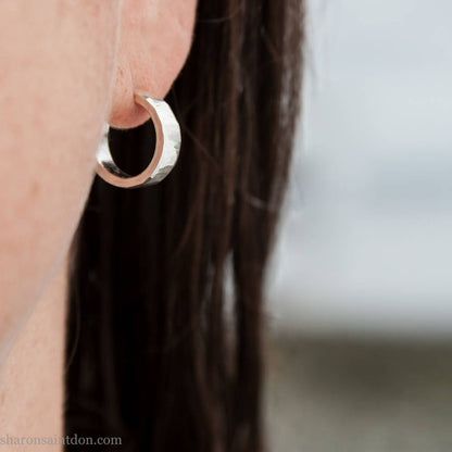 16 x 4mm x 1.5mm thick, 925 sterling silver hoop earrings handcrafted from solid, hand hammered real silver with a matte, brushed, shiny finish. Worn by a woman with light skin and dark, long, straight hair.