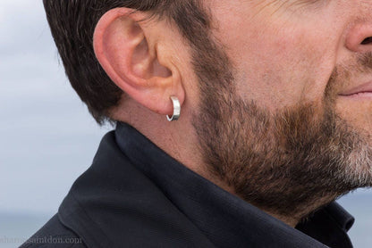 16 x 4mm x 1.5mm thick, 925 sterling silver hoop earrings handcrafted from solid, hand hammered real silver with a matte, brushed, shiny finish. Worn by a man with light skin, dark hair and beard.