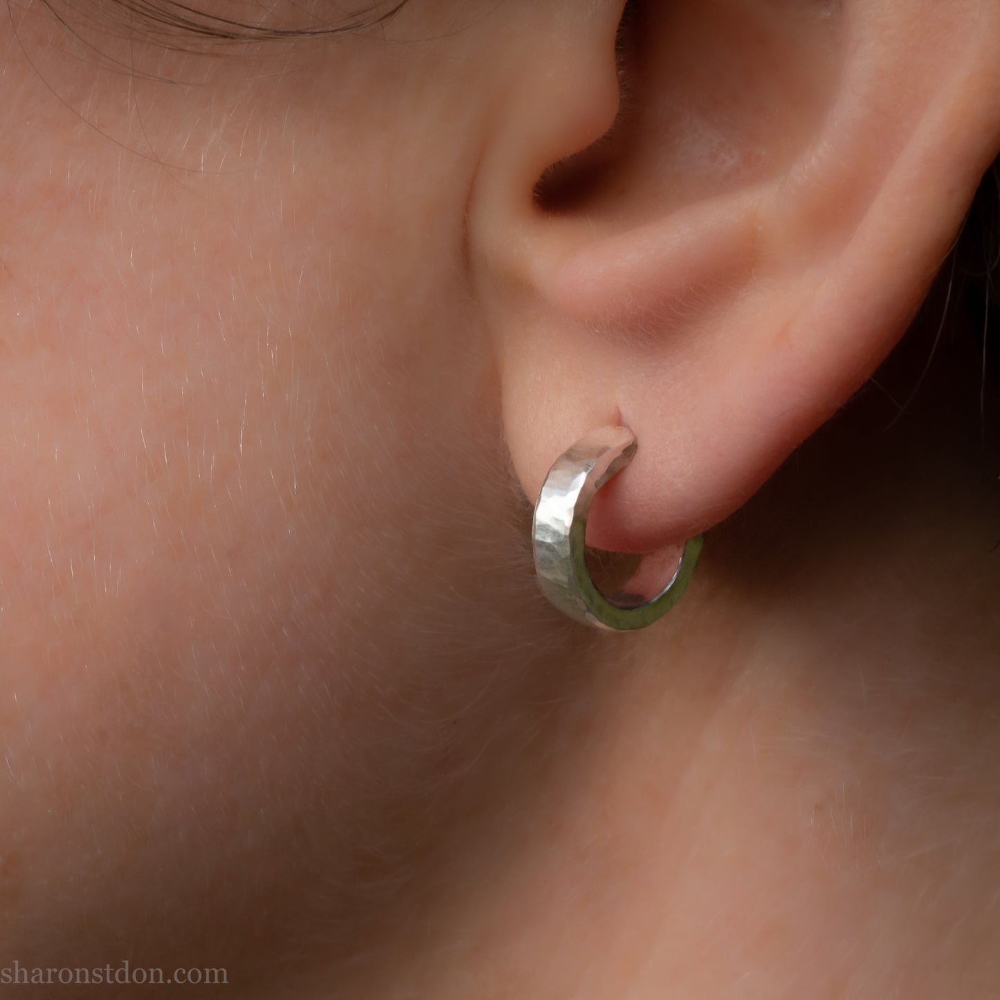 A close-up view of a person's ear with a silver hoop earring.