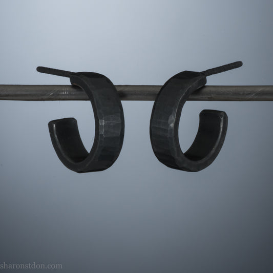 Close up photo of handcrafted oxidized black 14mm x 4mm hammered solid sterling silver hoop earrings.