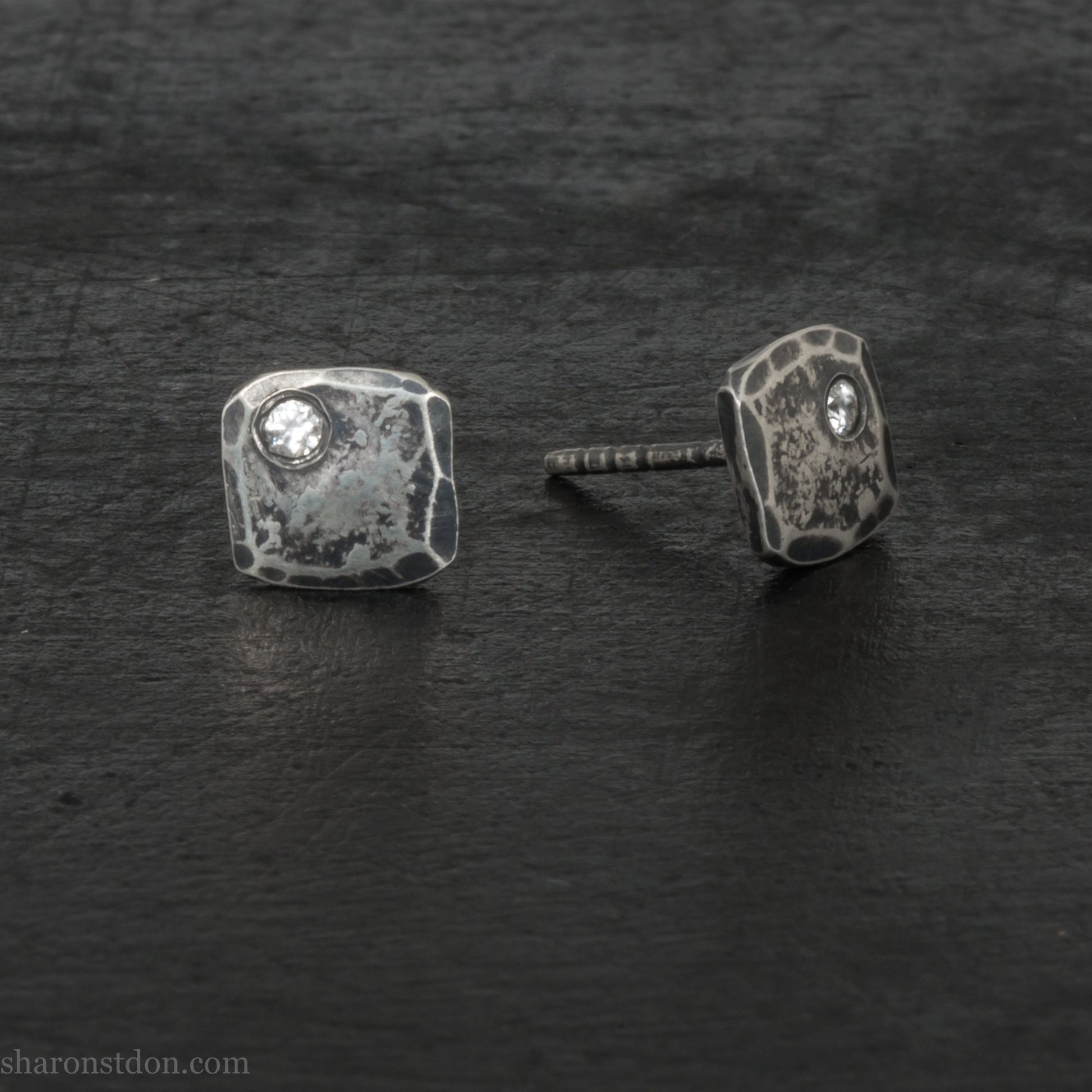 Small 925 sterling silver stud earrings for men with 2mm, imitation diamond gemstone set in the corner. 7mm square, 1.5mm thick with silver posts and backs and hammered, dark, antiqued finish. Handmade by Sharon SaintDon in North America.